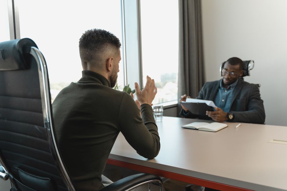 Een recruiter die een sollicitant interviewt met een notitieboek en pen, gericht op sterke vragen.